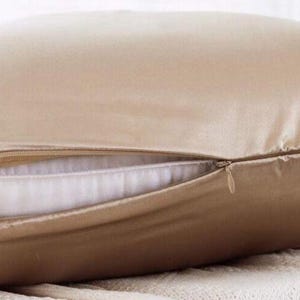 K&ouml;nnte beinhalten: Ein beigefarbener Kissenbezug aus Seide mit Rei&szlig;verschluss. Der Kissenbezug ist aus weicher, luxuri&ouml;ser Seide gefertigt und perfekt, um jedem Schlafzimmer einen Hauch von Eleganz zu verleihen.
