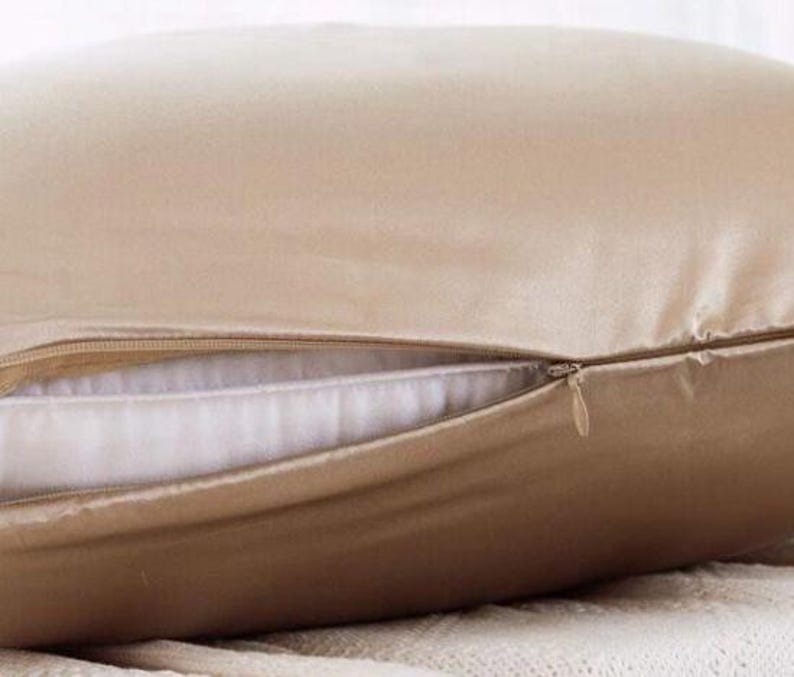 K&ouml;nnte beinhalten: Ein beigefarbener Kissenbezug aus Seide mit Rei&szlig;verschluss. Der Kissenbezug ist aus weicher, luxuri&ouml;ser Seide gefertigt und perfekt, um jedem Schlafzimmer einen Hauch von Eleganz zu verleihen.