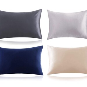 K&ouml;nnte beinhalten: Vier Satin-Kissenbez&uuml;ge in verschiedenen Farben: Grau, Silber, Marineblau und Beige. Die Kissenbez&uuml;ge sind in zwei Reihen zu je zwei angeordnet.