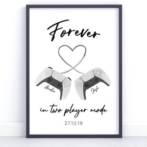 May include: A black framed print with the text "Forever in two player mode 27.10.18" and a heart shape formed by two white video game controllers.