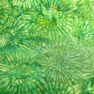 May include: A close-up of a green fabric with a repeating floral pattern. The design features stylized flowers in shades of green, with lighter green and yellow accents. The fabric has a textured appearance.