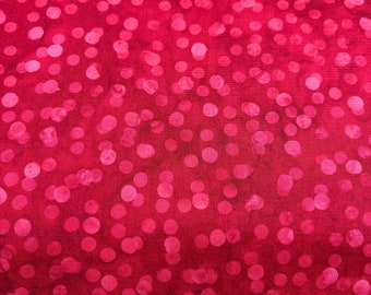 May include: Close-up of a red fabric with a pattern of pink polka dots. The dots vary in size and are scattered across the surface. The fabric has a textured appearance and a gradient effect, with darker shades at the edges.