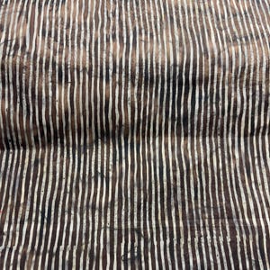 May include: A close-up of a fabric with a striped pattern. The stripes are white and brown, and they are arranged in a vertical pattern. The fabric is slightly wrinkled.