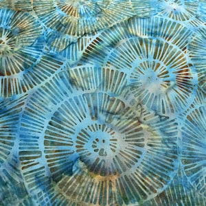 May include: A fabric featuring a repeating pattern of circular, sunburst-like motifs in shades of blue, teal, and hints of brown. The design consists of radiating lines that create a layered, organic effect across the surface of the textile.