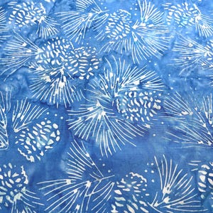May include: A blue fabric with a white pine cone and needle design. The pattern is repeated across the fabric, creating a textured and visually interesting surface. The fabric has a watercolor-like effect.