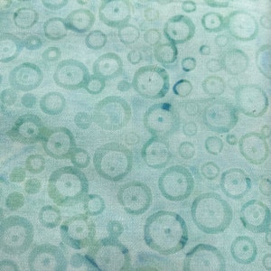 May include: A light blue fabric with a repeating pattern of green circles. The circles are of varying sizes and are slightly faded.