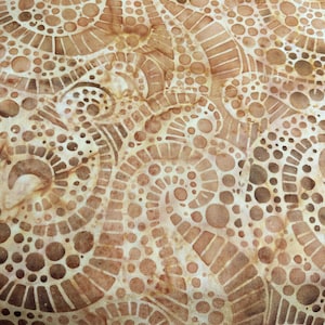 May include: Close-up of a fabric with a repeating pattern of brown and tan swirls, circles, and geometric shapes. The design has a batik-like appearance, with variations in color and texture.