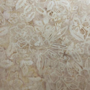 May include: Close-up of fabric with a floral pattern. The fabric has a beige background with a repeating design of white flowers and leaves. The floral pattern is detailed and covers the entire surface.