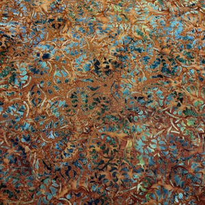 May include: Close-up of a fabric with a repeating floral pattern. The fabric features a blend of warm brown and orange hues, with accents of blue and green. The design has a batik-like appearance, with intricate details.