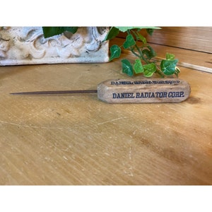 May include: A wooden tool with a metal tip, branded with "DANIEL RADIATOR CORP."