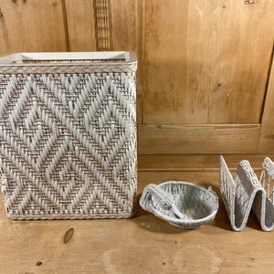 May include: A woven wicker wastebasket, small basket, and a magazine holder. The wastebasket is rectangular with a diamond pattern. The small basket has a handle and a spoon. The magazine holder has a zig-zag design.