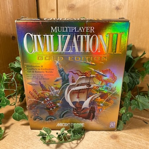 May include: A Civilization II Gold Edition game box. The box features a colorful illustration of a sailing ship, the Statue of Liberty, and other historical elements. The text "MULTIPLAYER CIVILIZATION II GOLD EDITION" is prominently displayed.