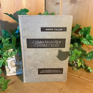 May include: A gray hardcover book titled "A Modern Introduction to Geometries" by Annita Tuller. The book is part of "The University Series in Undergraduate Mathematics".