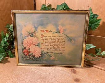 May include: A framed print with a gold-colored frame. The artwork features a floral arrangement of peach-colored flowers and a poem dedicated to "Mother." The text is in a decorative font, set against a soft blue and green background.