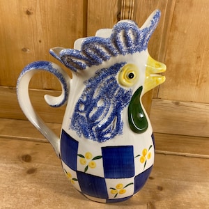 May include: A white ceramic mug with a black handle and the text "But First, Coffee" in a black, handwritten-style font. The mug is on a white surface.