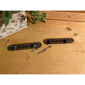 May include: Two antique brass drawer pulls with a decorative design and four screws.