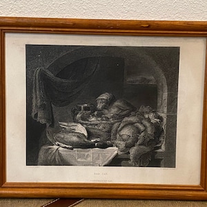 May include: A black and white engraving of a still life featuring a monkey, a bowl of fruit, and a loaf of bread. The engraving is framed in a wooden frame.
