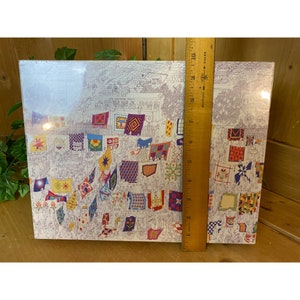 Może przedstawiać: Winietkowa ilustracja przedstawiająca wystawę patchwork&oacute;w z r&oacute;żnorodnymi kolorowymi patchworkami prezentowanymi na białym tle. Tekst "The Lancaster County Quilt Show" jest widoczny w g&oacute;rnej części obrazu.
