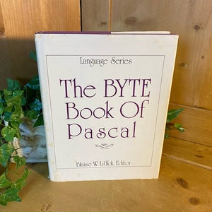 May include: A white book with a purple spine titled "The BYTE Book Of Pascal" with the subtitle "Language Series" and the author "Blaise W. Liffick, Editor".