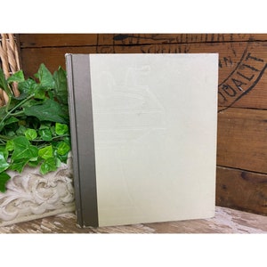 May include: A vintage hardcover book with a white cover and a gray spine. The cover has a subtle embossed design of a pitcher and a glass.