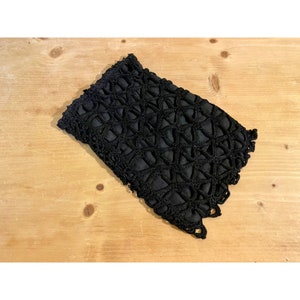 May include: Black crocheted clutch bag with a geometric pattern.