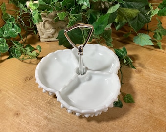 May include: A white milk glass three-section serving dish featuring a hobnail pattern along the outer rim and a central silver-toned metal handle with a triangular loop at the top for carrying the divided tray.
