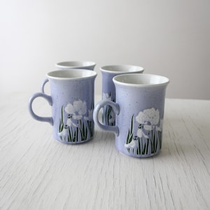 May include: Set of four blue ceramic mugs with white floral designs. The mugs have a speckled glaze and are perfect for everyday use.