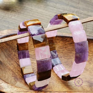 May include: Two bracelets made of square-shaped gemstone beads. One bracelet is made of amethyst, tiger's eye, and rose quartz beads. The other bracelet is made of amethyst and rose quartz beads.