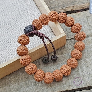 Può includere: Un braccialetto mala marrone con un fiocco marrone scuro. Il braccialetto è composto da 108 perline ed è infilato su un cordoncino marrone.