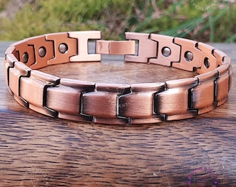 May include: A copper magnetic bracelet with a brushed finish. The bracelet has a clasp and is made of multiple links.