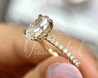 Puede incluir: Un anillo de compromiso de oro con un gran diamante de forma ovalada y una banda de diamantes más pequeños.