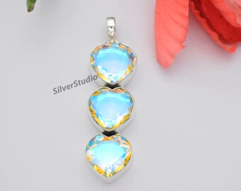 May include: A silver pendant with three iridescent heart-shaped stones. The stones are a light blue color with a rainbow sheen.