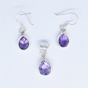 May include: A set of sterling silver earrings and a pendant featuring a teardrop-shaped amethyst gemstone. The earrings have a hook closure and the pendant has a bail for attaching to a chain.
