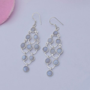 Puede incluir: Un par de pendientes colgantes de plata con piedras de ágata azul claro. Los pendientes tienen un diseño en cascada con varias piedras.