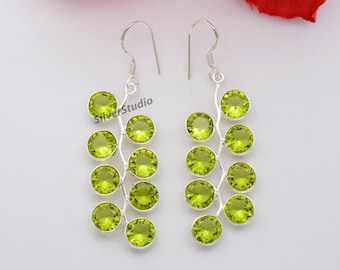May include: Silver earrings with a branch design featuring multiple green gemstones.