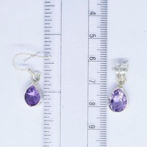 May include: A pair of sterling silver earrings and a pendant featuring a teardrop-shaped amethyst gemstone. The earrings are approximately 1 inch long and the pendant is approximately 1.5 inches long.