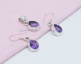 May include: A set of sterling silver earrings and a pendant featuring a teardrop-shaped amethyst gemstone. The earrings have a hook closure.