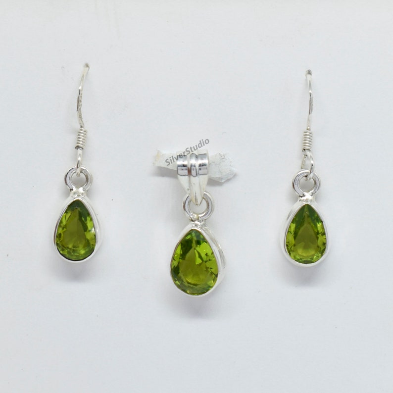 May include: A set of silver earrings and a pendant featuring pear-shaped green gemstones.