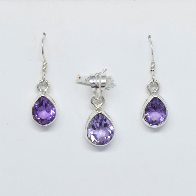 May include: A set of sterling silver earrings and a pendant featuring a teardrop-shaped amethyst gemstone. The earrings have a simple hook closure. The pendant has a bail for attaching to a chain.