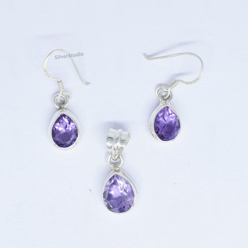 May include: A set of sterling silver earrings and a pendant featuring a teardrop-shaped amethyst gemstone. The earrings have a hook closure and the pendant has a bail for attaching to a chain.
