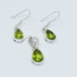 May include: A set of silver earrings and a pendant featuring pear-shaped green peridot gemstones.