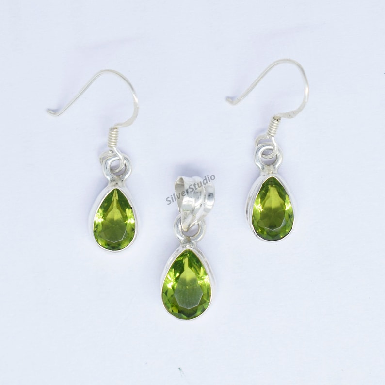 May include: A set of silver earrings and a pendant featuring green gemstone drops.