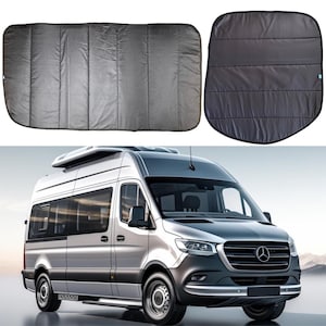May include: A silver van with a pop-up roof and black window shades. The van has a Mercedes-Benz logo on the front grille.