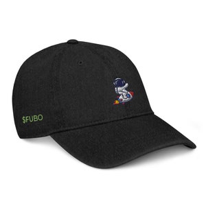Puede incluir: Gorra de béisbol negra con un diseño de astronauta bordado y el texto "$FUBO" en verde en la parte delantera.