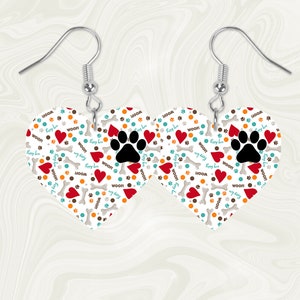 May include: A pair of heart-shaped earrings with a white background and a pattern of red hearts, brown bones, blue paw prints, and the text "WOOF!" and "Puppy Love".