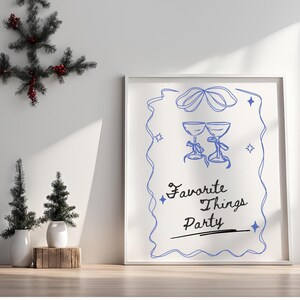 Op de afbeelding: Een witte ingelijste print met een blauwe illustratie van twee glazen met een blauw lint en de tekst "Favorite Things Party" in zwarte cursieve letters.