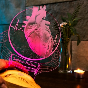 Someone is holding the heart surgeon lamp by the corner and holding it up. The lamp is shines pink.
