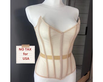 Puede incluir: Un corsé beige con una capa transparente y ballenas verticales. El corsé tiene un escote corazón y una banda beige en la cintura. El texto "NO TAX for USA" está en una tarjeta pequeña.