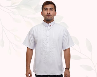 May include: White short-sleeved shirt with a mandarin collar and decorative pleats down the front. The shirt has a small emblem on the collar. The shirt is paired with black pants. The shirt is made of a lightweight fabric.