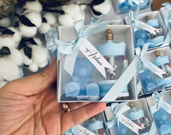 May include: Blue and white favour boxes with a carousel design and a blue bear. The boxes are tied with a blue ribbon and have a white tag with the name "Aslan" written on it.